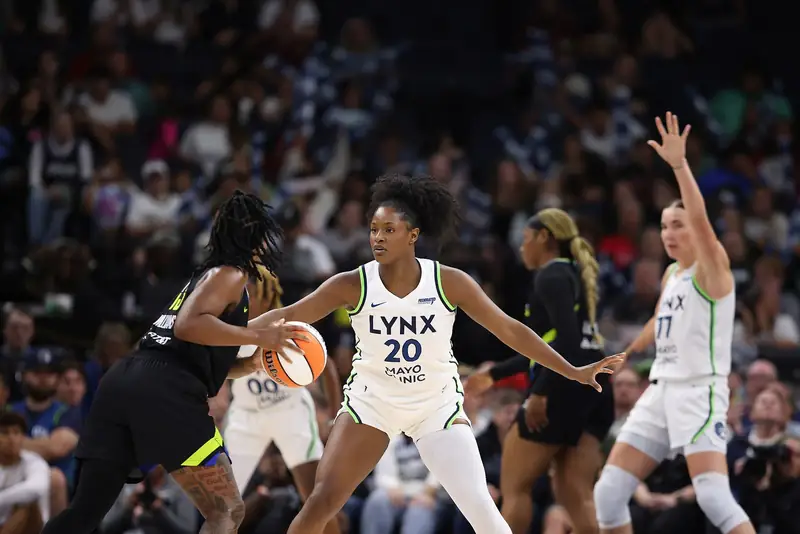 A Minnesota Lynx defender guards a Dallas Wings ball handler at the top of the key.